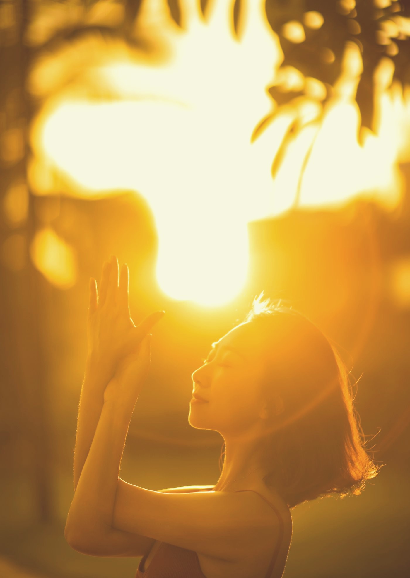 A woman meditating outdoors at sunrise.